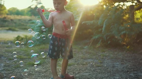 Child playing with soap bubbles  in sunset lens flare  Stock Footage 79961673