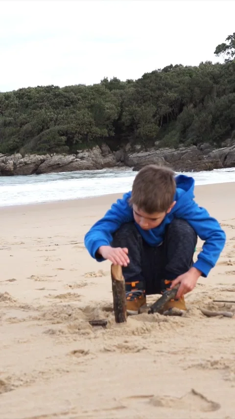 Child playing with some sticks on the seashore on a virgin beach Stock Footage 260798586