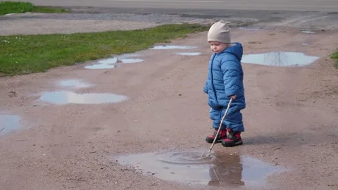 Child Playing with stick in Puddles Stock Footage 303498057