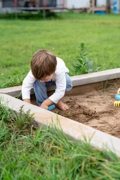 Child playing in summer sandbox, capturing authentic everyday creativity an.. Stock Photos