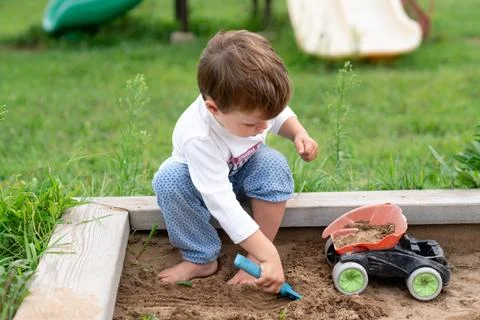 Child playing in summer sandbox, capturing authentic everyday creativity an.. Stock Photos