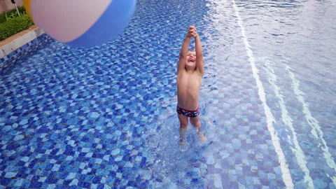 Child playing in swimming pool with inflatable beach ball Stock Footage 303621739