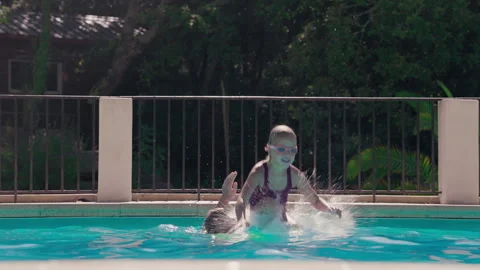 Child playing in swimming pool with splash and joyful jump Stock Footage 319879301