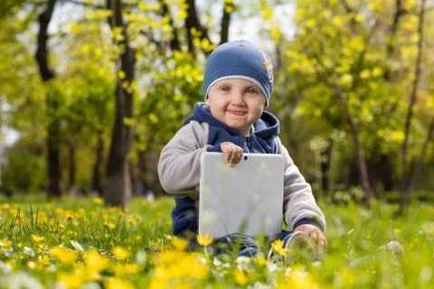 Child playing with tablet in the park. Stock Photos