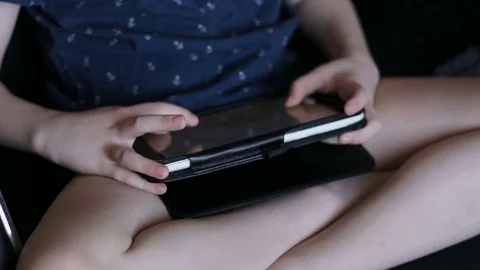 A child is playing a tablet. Sits in an office chair Stock Footage 74972472