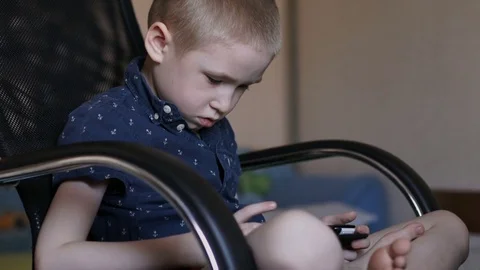 A child is playing a tablet. Sits in an office chair Stock Footage 74976206