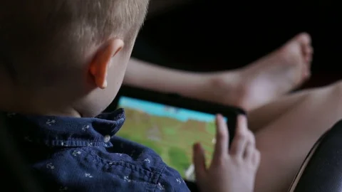 A child is playing a tablet. Sits in an office chair Stock Footage 74977106