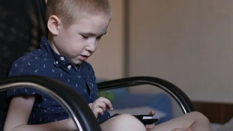 A child is playing a tablet. Sits in an office chair, slow motion Stock Footage 74977528