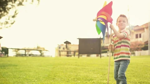 Child is playing at town park in summer day with pinwheel Video stock 64530282