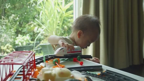 Child Playing with Toy Train on Table by Window Stock Footage 341143309