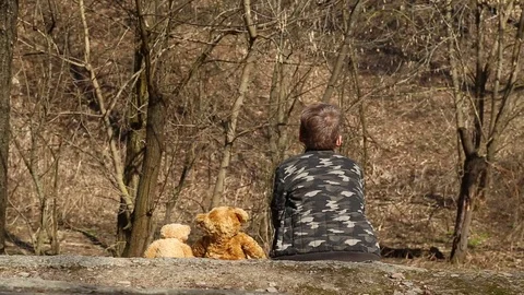 Child playing with two cute brown soft toy bears outside on spring sunny day Stock Footage