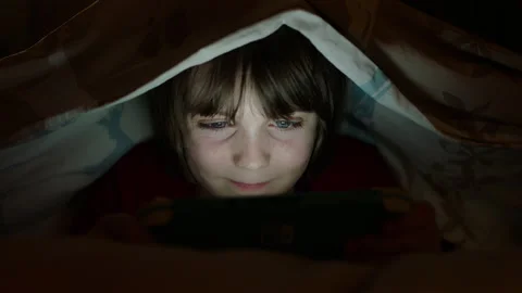 Child playing video games console at home in bed under duvet 4k Stock Footage 143571997