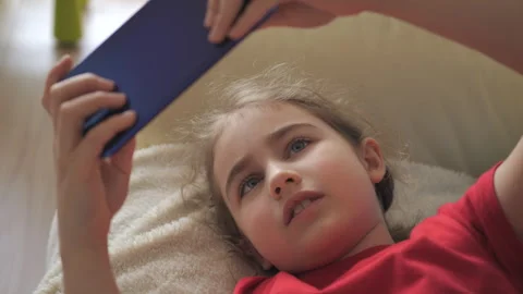 Child Playing Video Games In Mobile Phone at Home Lying on Couch. Mobile ph.. 库存影片 335598186