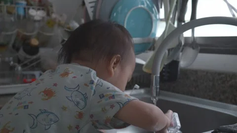 Child Playing with Water in Kitchen Sink Stock Footage 345662696