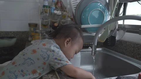 Child Playing with Water in Kitchen Sink Stock Footage 345662723