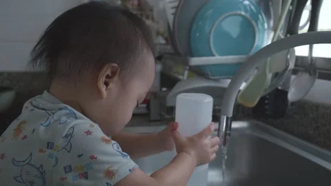 Child Playing with Water at Kitchen Sink Stock Footage 345662747