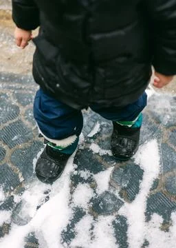 Child playing in winter snow while wearing warm clothing and boots during a cold Stock Photos