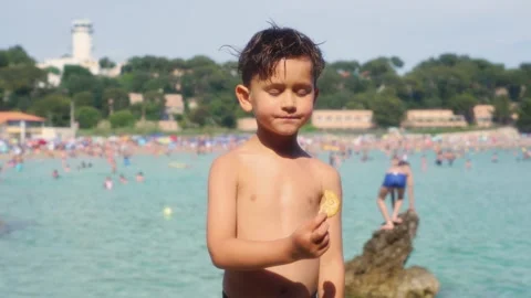 A child plays on the beach and eats his snack in the sea in France Stock Footage 286722395