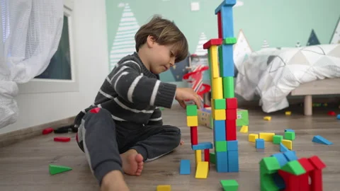 Child plays with building blocks on floor. Lifestyle shot of kid accidental.. Vídeo Stock 228858239