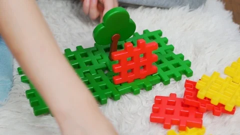  The child plays with the colored blocks of the constructor, sitting on a white  Stock Footage 117622541