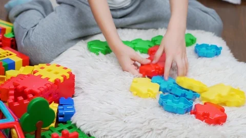 A child plays with colored blocks puzzle designer on a white rug wooden floor. T Stock Footage 118505751