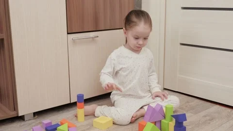 Child plays with colored cubes in children's room on the floor. The kid is Stock Footage 148132285