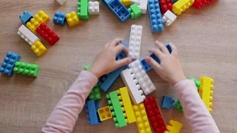 Child plays with a constructor from colored bricks blocks, top view Stock Footage 221333110
