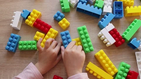 Child plays with a constructor from colored bricks blocks, top view Stock Footage 221333119