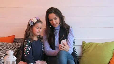 The child plays a digital tablet, mom smiles and hugs her. Stock Footage 133306656