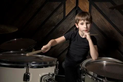 The child plays the drums. Boy musician behind a drum kit. Stock Photos