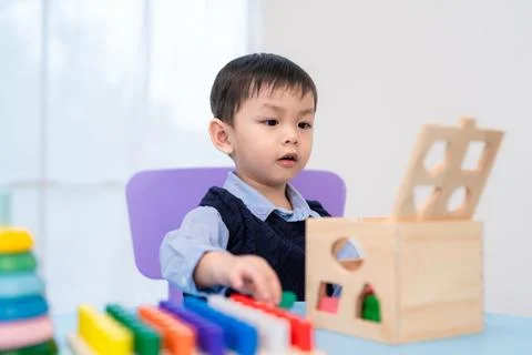 Child plays with educational toy at a table in a bright room during the day Stock Photos