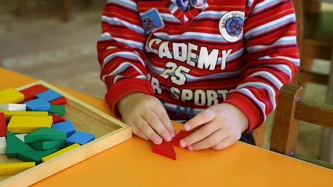 A child plays with the figures on the table. The child is wearing red clothes Stock Footage 129813269