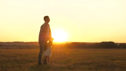 Child plays fly with dad at sunset in field. father circles his beloved daughter Stock Footage 133145967