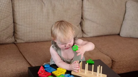 Child plays at home with a colored educational wooden toy, sitting on the sofa Stock Footage 265174204