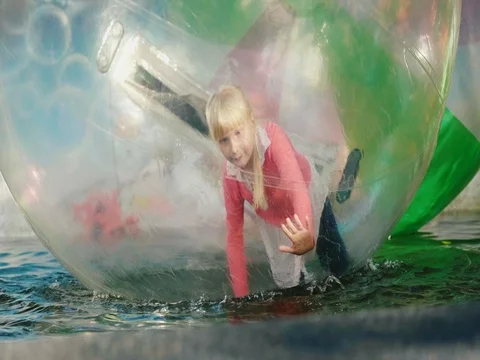 The child plays inside a transparent ball on the water. Recreation in amusement Stock Footage 79844706