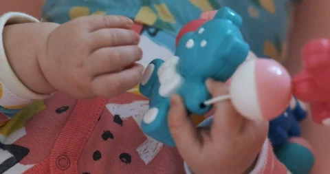 Child plays lying on bed and with rattle, toy birch bear, close-up baby handles Stock Footage 122904886