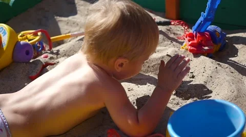 The child plays lying in the sandbox 库存影片 66797833