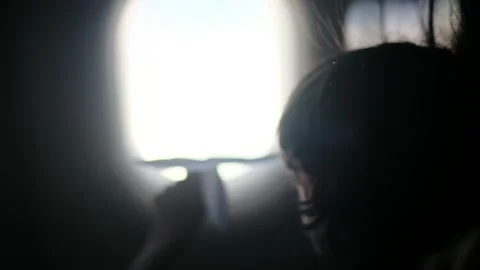 Child plays with a paper airplane inside an airplane looking out the window Stock Footage 252036681