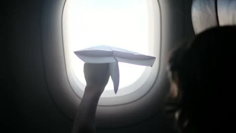 Child plays with a paper airplane inside an airplane looking out the window Stock Footage 252036686