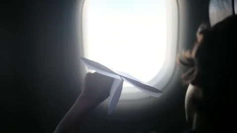 Child plays with a paper airplane inside an airplane looking out the window Stock Footage 252036689