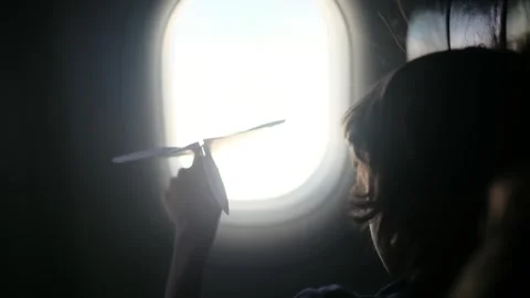 Child plays with a paper airplane inside an airplane looking out the window Stock Footage 252036691