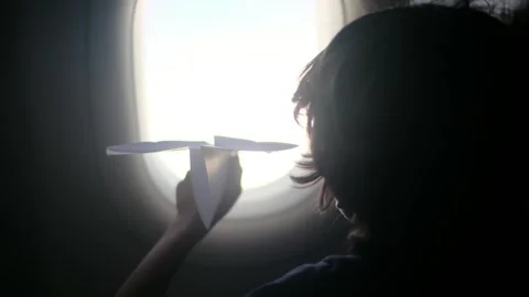 Child plays with a paper airplane inside an airplane looking out the window Stock Footage 252036693