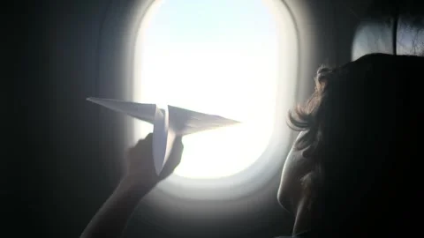 Child plays with a paper airplane inside an airplane looking out the window Stock Footage 252036695