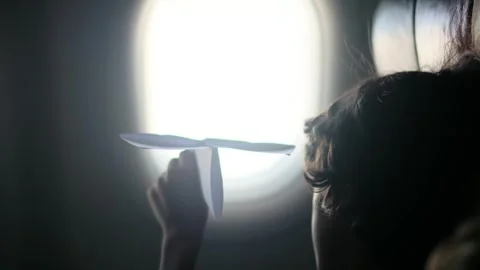 Child plays with a paper airplane inside an airplane looking out the window Stock Footage 252036702