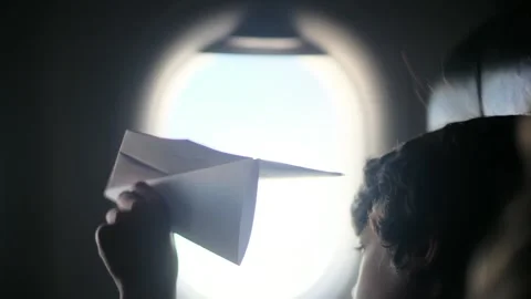 Child plays with a paper airplane inside an airplane looking out the window Stock Footage 252036703