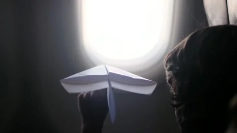 Child plays with a paper airplane inside an airplane looking out the window Stock Footage 252036705