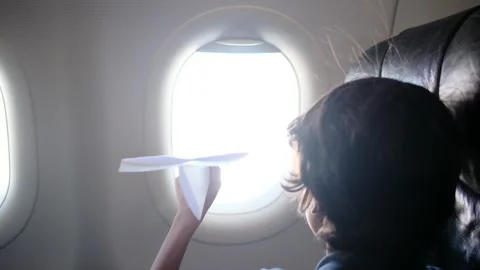 Child plays with a paper airplane inside an airplane looking out the window Stock Footage 252036708