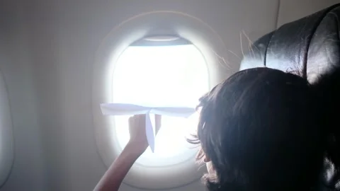 Child plays with a paper airplane inside an airplane looking out the window Stock Footage 252036713