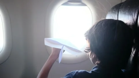 Child plays with a paper airplane inside an airplane looking out the window Stock Footage 252036718