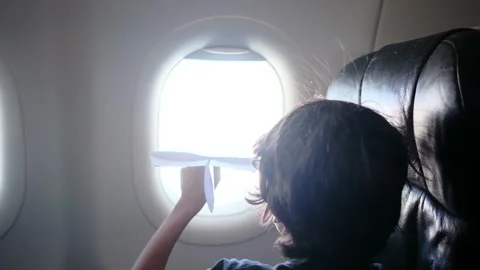 Child plays with a paper airplane inside an airplane looking out the window Stock Footage 252036719